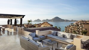 A rooftop terrace with outdoor seating, a pergola, and a view of the sea and mountains.