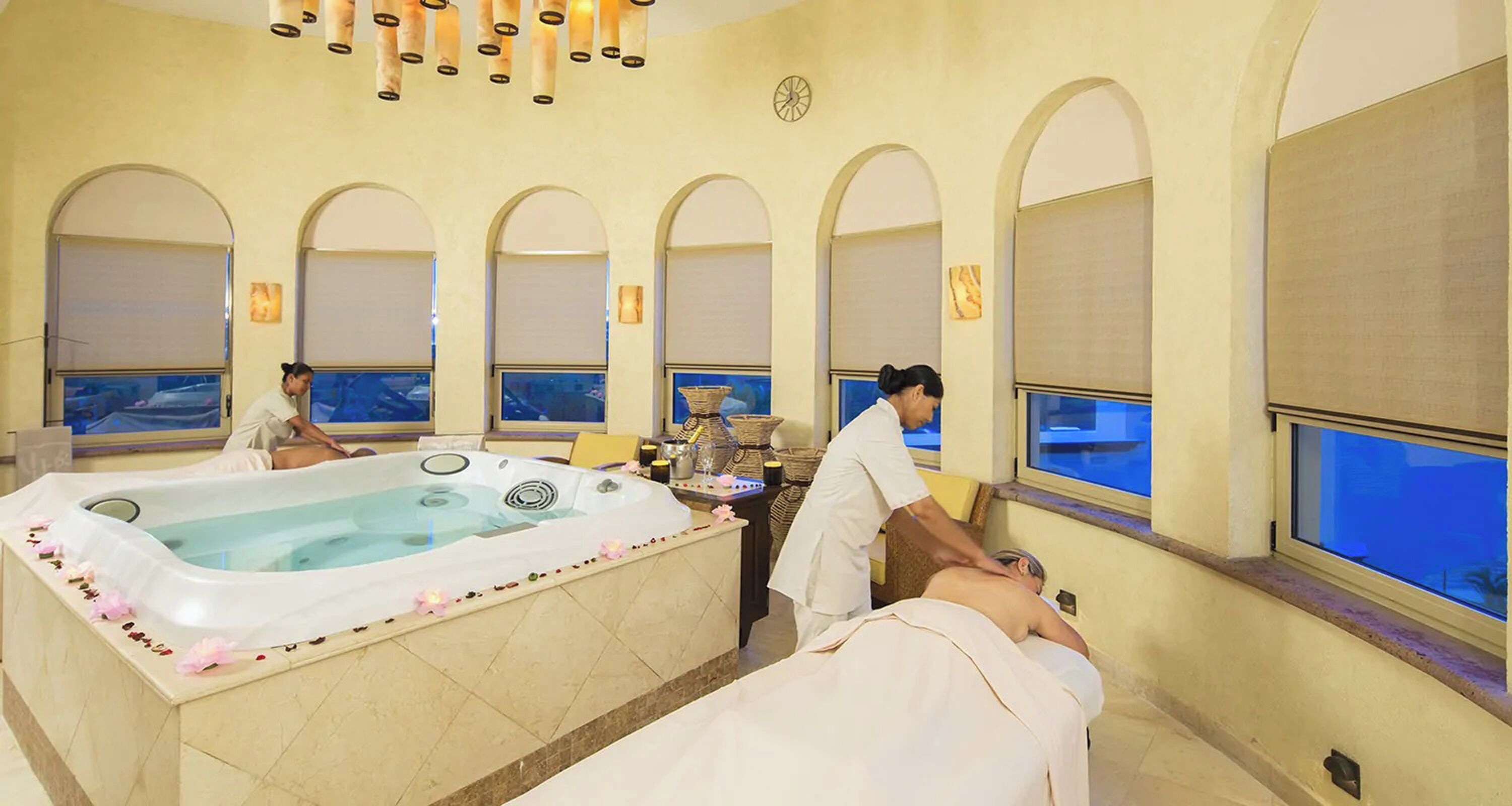 Ein Spa-Zimmer mit einer großen Badewanne, Bogenfenstern und Meerblick.