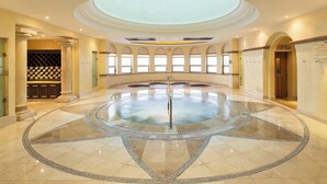 A spacious indoor area with a central circular water feature, arched windows, and a wine cellar.