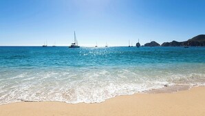 A beach with clear blue water and boats.
