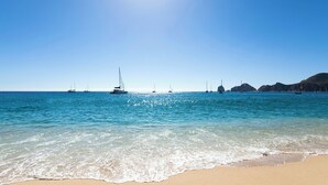 Une plage avec une eau turquoise et limpide, des bateaux et une rive sablonneuse.