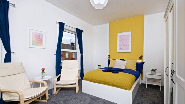 A bedroom with a bed, two chairs, a small table, and a nightstand. - Comfortable Room in Shared House (Liverpool)