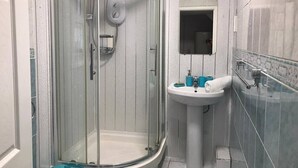 A modern bathroom with a glass-enclosed shower, a pedestal sink, and a mirror above it. - Comfortable Room in Shared House (Liverpool)