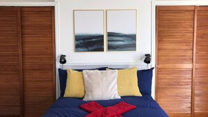 A bedroom with a bed, pillows, a blanket, and two wall-mounted lamps.