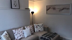 Un salon avec un canapé, des coussins, une lampe sur pied et des œuvres d’art murales.