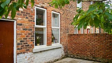 A brick house with two windows, a white door, and a brick wall.