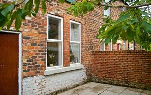 A brick house with two windows, a white door, and a brick wall. - Experience Comfort in Liverpool (Merseyside)