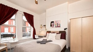 Een hotelkamer met een bed, een bureau, een stoel, een kledingkast en een raam met gordijnen.
