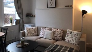 A cozy living room with a sofa, a round coffee table, and a floor lamp. - Experience Comfort in Liverpool (Merseyside)