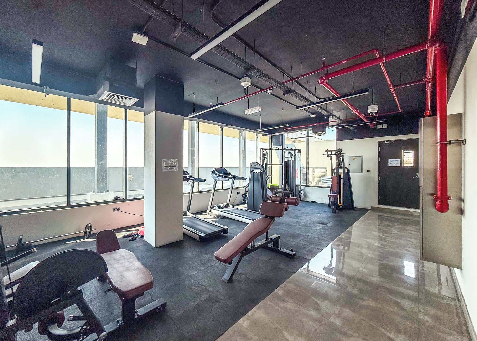 Un gimnasio con cintas de correr, máquinas de pesas y bancos.