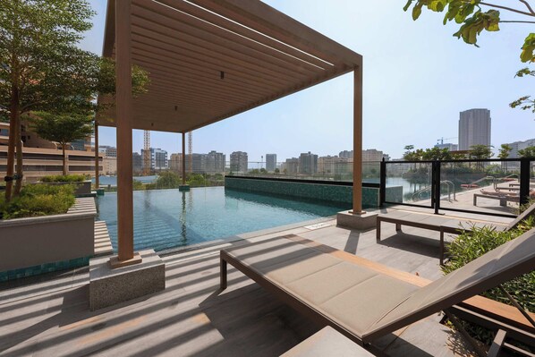 Un espace piscine aménagé sur le toit, avec des chaises longues et une pergola.