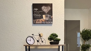 A kitchen area with a coffee machine, a clock, and a small bicycle decoration on a shelf.