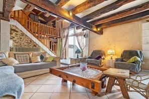 A rustic interior with a wooden staircase, a sofa, a coffee table, and a chair.