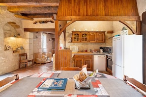 Une cuisine rustique avec des meubles en bois, une table à manger avec un set de table et un livre posé sur la table.