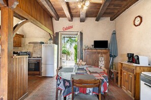 A rustic kitchen with wooden beams, a dining table with a tablecloth, a clock on the wall, and a sign that reads 'Cuisine'. - Le Séchoir d'Alice: Holiday Home with Private Terrace, Garden & Wi-Fi (Saint-Germain du Salembre)