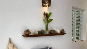 Une pièce chaleureuse avec un lit en bois, une étagère ornée d’objets décoratifs et un luminaire fixé au mur.