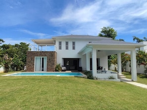 Une maison moderne à deux étages, dotée d’une piscine, d’un patio couvert et d’une pelouse bien entretenue.