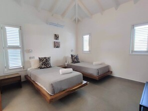 Une chambre avec deux lits, des murs blancs et un plafond en pente.