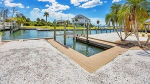 A marina with a dock, a house in the background, and palm trees. - Experience waterfront vacation  living (Englewood)