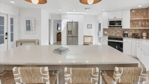 A modern kitchen with a large island, stainless steel appliances, and pendant lighting. - Experience waterfront vacation  living (Englewood)