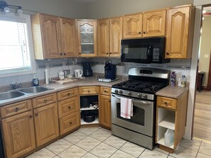 A kitchen with wooden cabinets, a stainless steel stove, a microwave, and a coffee maker.