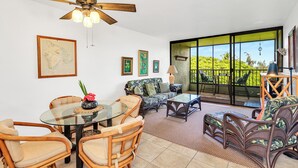 A spacious living area with a glass table, wicker chairs, a sofa, and a ceiling fan. - Sea Turtle Suite - Steps from Carlsmith Beach! (Hilo)