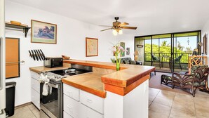 A kitchen with a central island, a microwave, and a stove. There are chairs and a table outside the kitchen. - Sea Turtle Suite - Steps from Carlsmith Beach! (Hilo)
