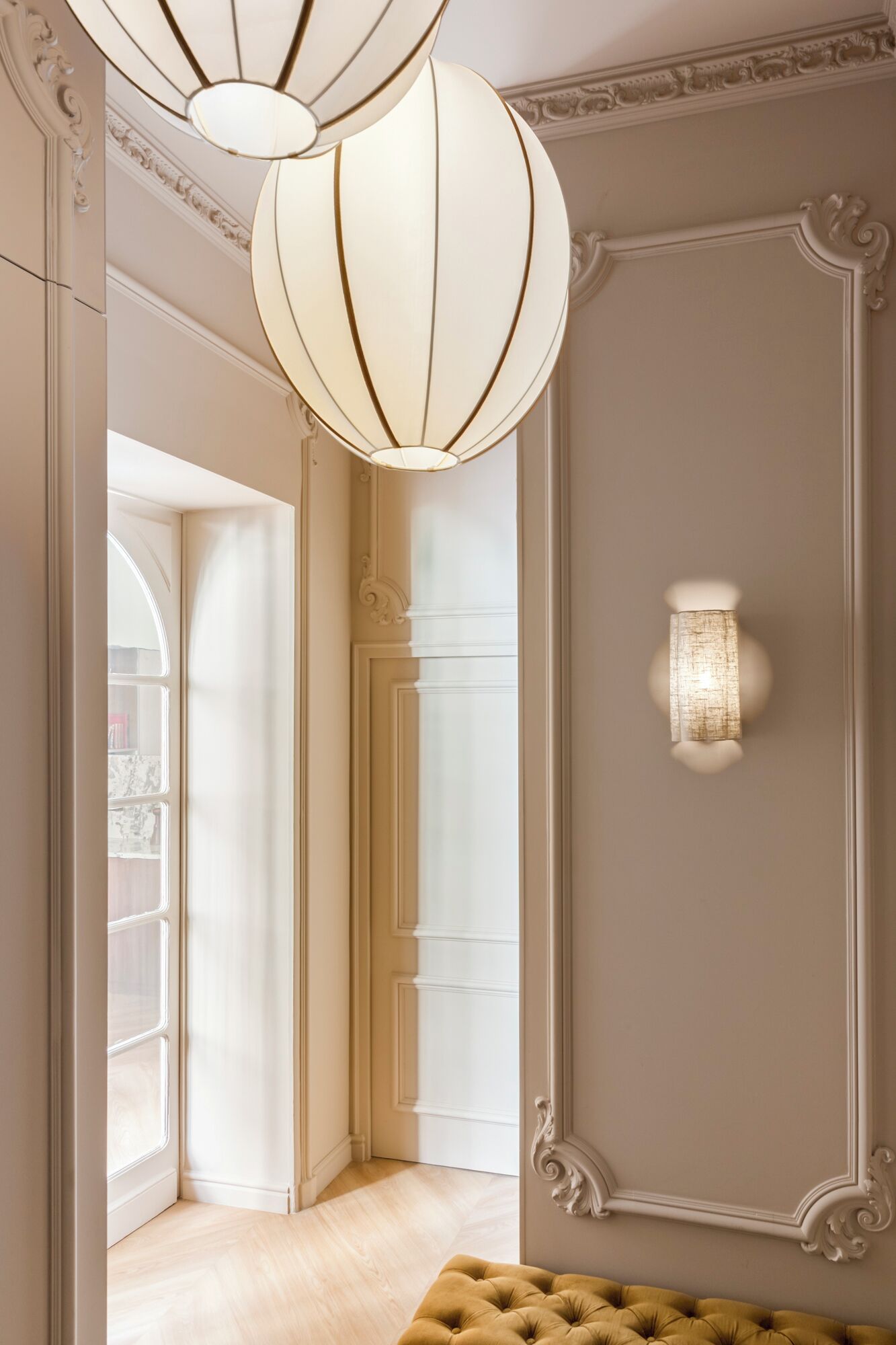 A hallway with a white door, a light fixture, and a wall-mounted light.