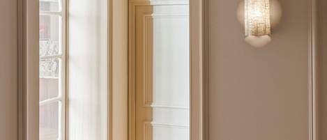 A hallway with a white door, a light fixture, and a wall-mounted light.