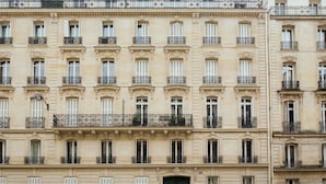 A multi-story building with uniform architectural style, featuring evenly spaced windows and balconies with wrought iron railings. - Merveil Signature Suite - Marignan (Paris)