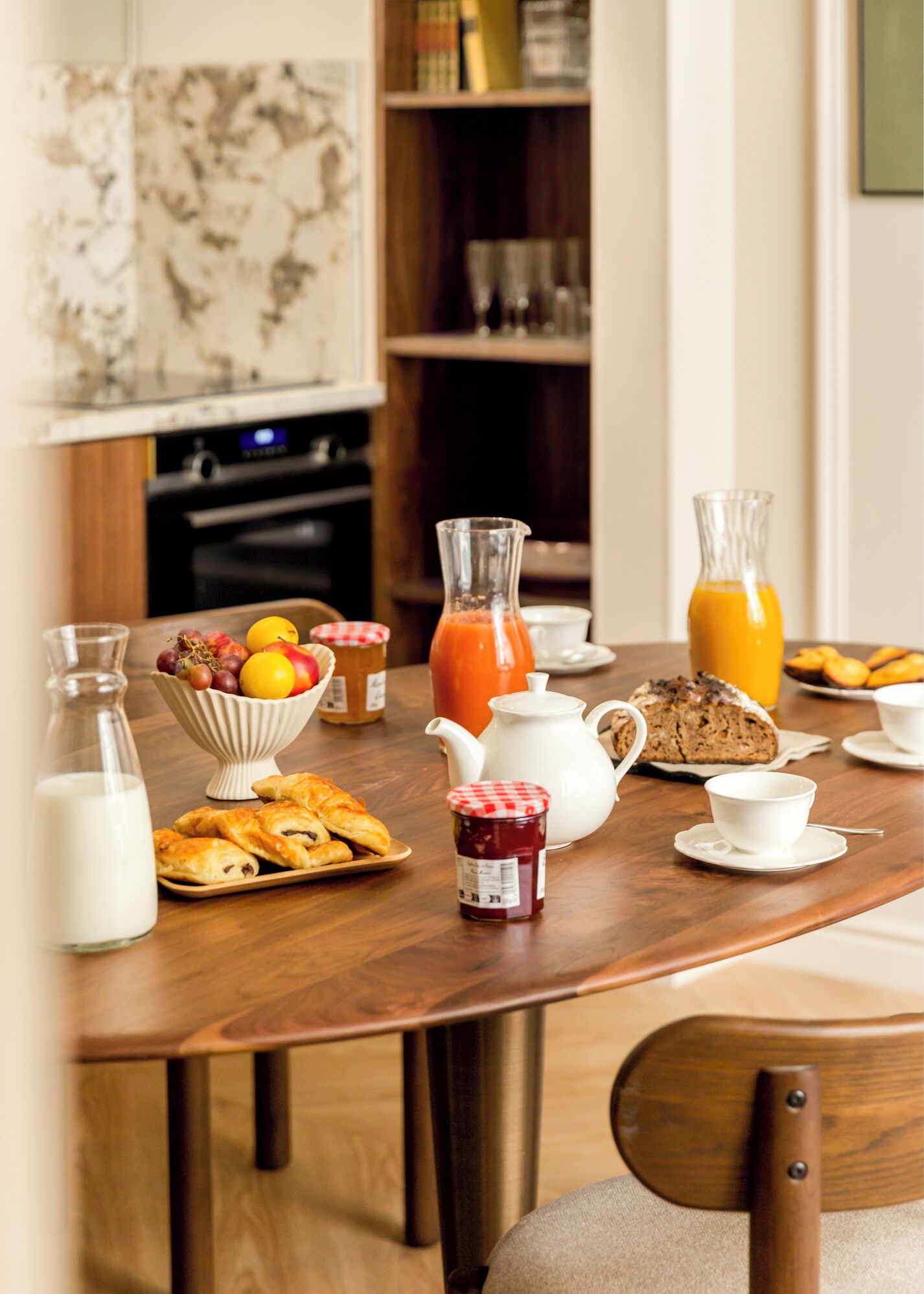A breakfast table with a variety of food items, including pastries, fruits, and beverages.