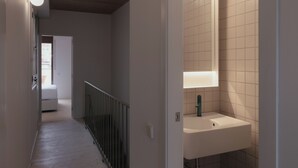 A hallway with a white sink and mirror, wooden flooring, and a staircase with a metal railing. - Casa Flor Duplex Boutique Mid-term Barcelona (Barcelona)