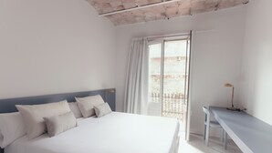 A bedroom with a bed, a desk, and a view of the outside. - Casa Flor Duplex Boutique Mid-term Barcelona (Barcelona)