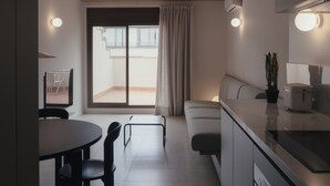 A modern kitchen with a dining area, a sofa, and a large window with curtains. - Casa Flor Duplex Boutique Mid-term Barcelona (Barcelona)