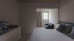 A bedroom with a large bed, a dresser, a chair, and a window with curtains. - Casa Flor Duplex Boutique Mid-term Barcelona (Barcelona)