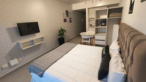 A modern bedroom with a bed, a TV, a small table, a chair, and a wardrobe. - Vianzo BA (Buenos Aires)