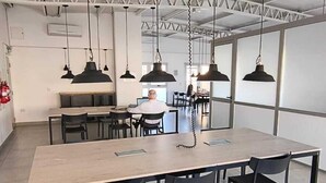 A spacious dining area with a long table and chairs, overhead lighting, and a kitchen in the background. - Vianzo BA (Buenos Aires)