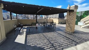 An outdoor patio with tables and chairs, a covered seating area, and a view of the cityscape. - Vianzo BA (Buenos Aires)