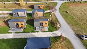 Un quartier résidentiel moderne composé de maisons compactes aux façades en bois et aux toits en métal, disposées autour d’une allée centrale.