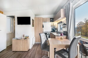Une cuisine moderne avec un coin repas, un téléviseur à écran plat et une vue sur l’extérieur.