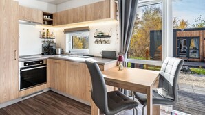 A modern kitchen with wooden cabinets, a built-in oven, and a dining area with a table and chairs.