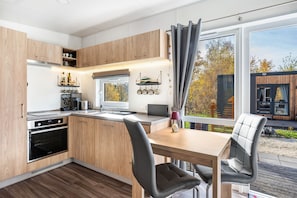 Eine moderne Küche mit Holzausstattung, einem Einbauofen und einem Essbereich mit Tisch und Stühlen.