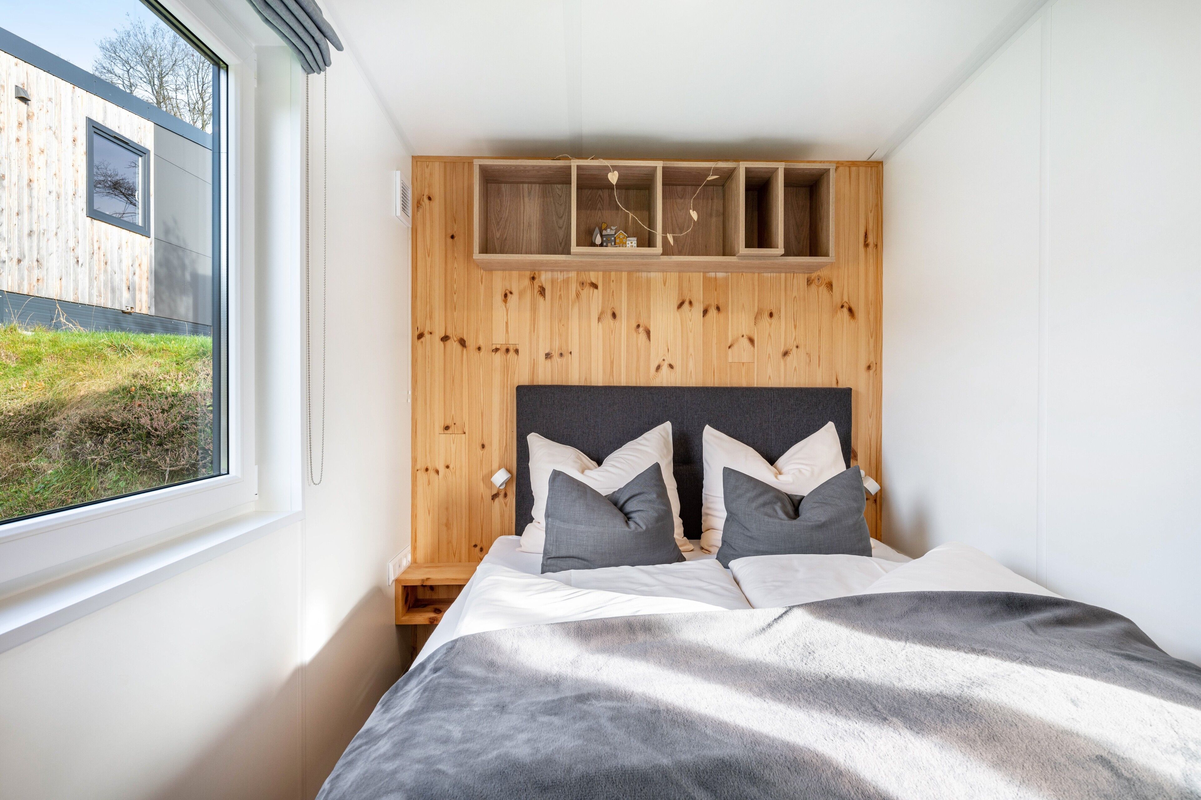 A bedroom with a bed, a window, and a wooden headboard.