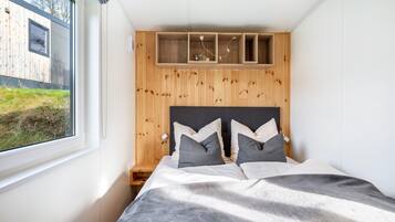 A bedroom with a bed, a window, and a wooden headboard.