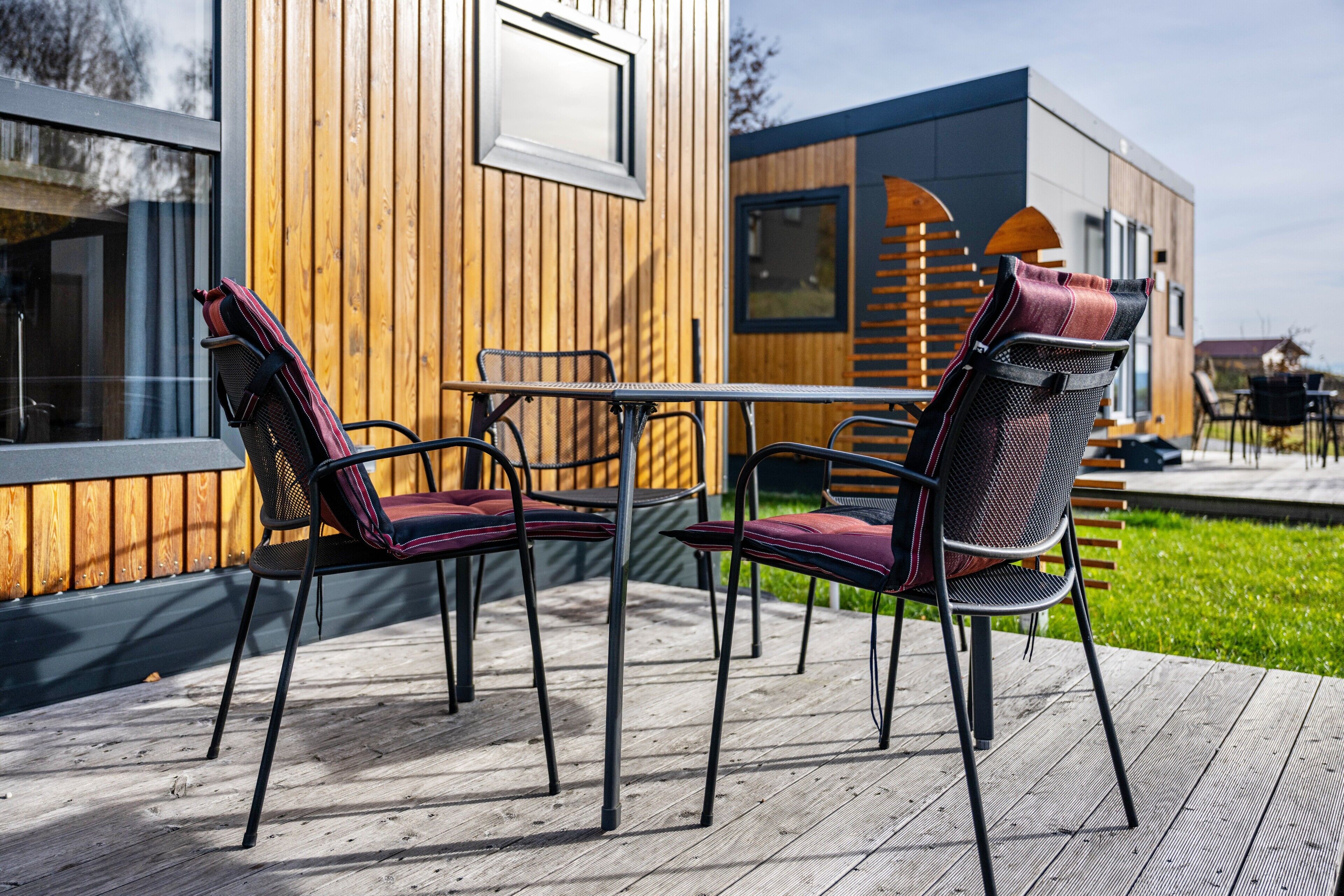 Una terraza de madera con sillas de metal y una mesa.