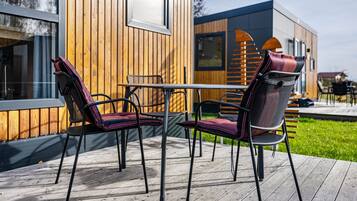 Una terraza de madera con sillas de metal y una mesa.