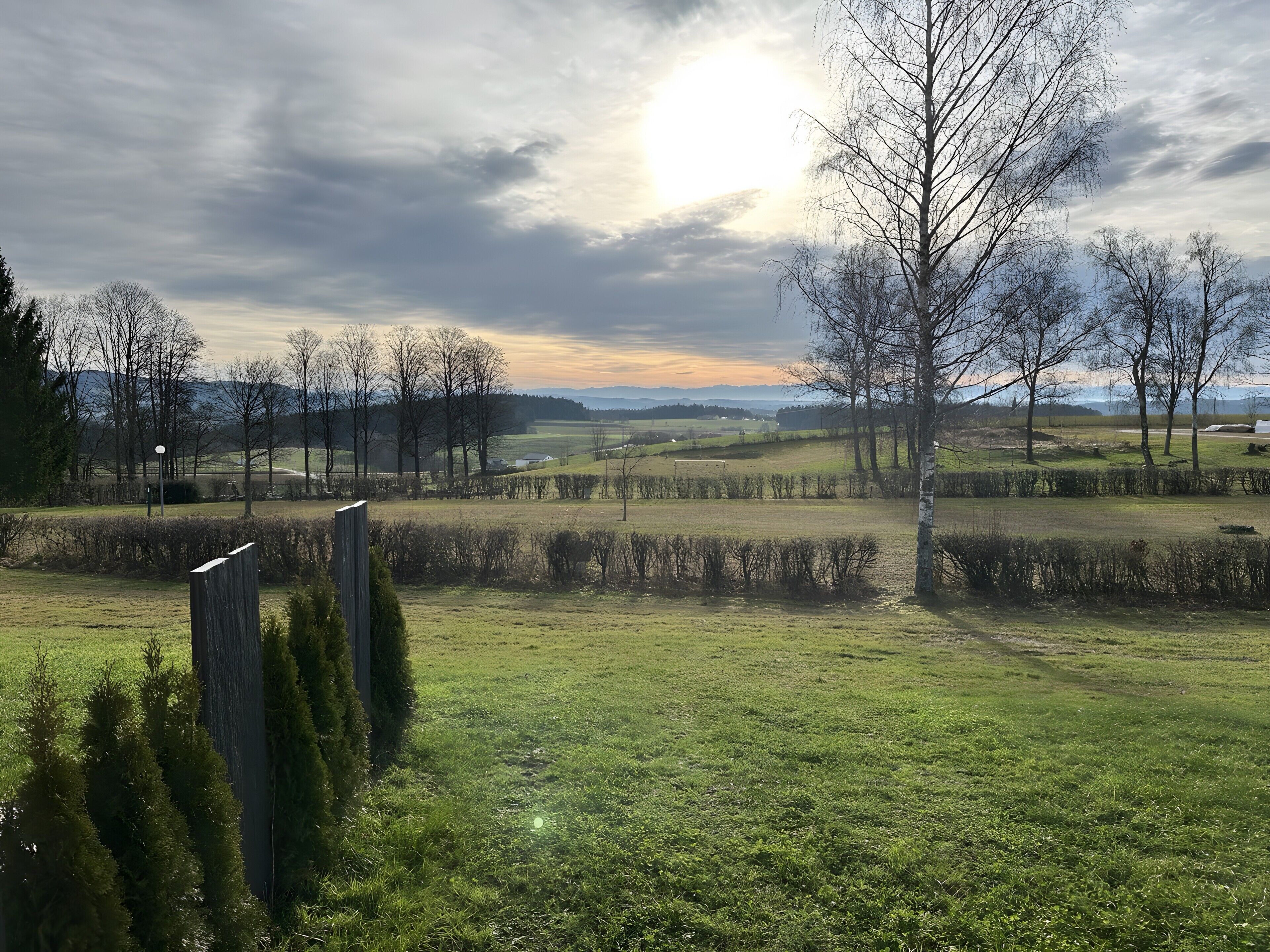 A rural landscape with open fields, trees, and a clear sky.