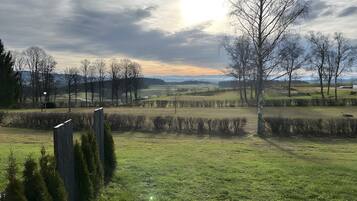 A rural landscape with open fields, trees, and a clear sky.
