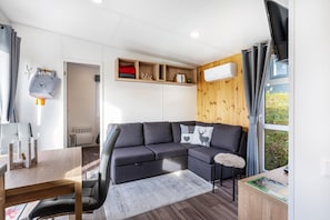 Un salon moderne comprenant un canapé d’angle, une table à manger et une étagère intégrée avec espace de rangement.