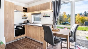 Une cuisine moderne avec des meubles en bois, un four encastré et un coin repas comprenant une table et des chaises.